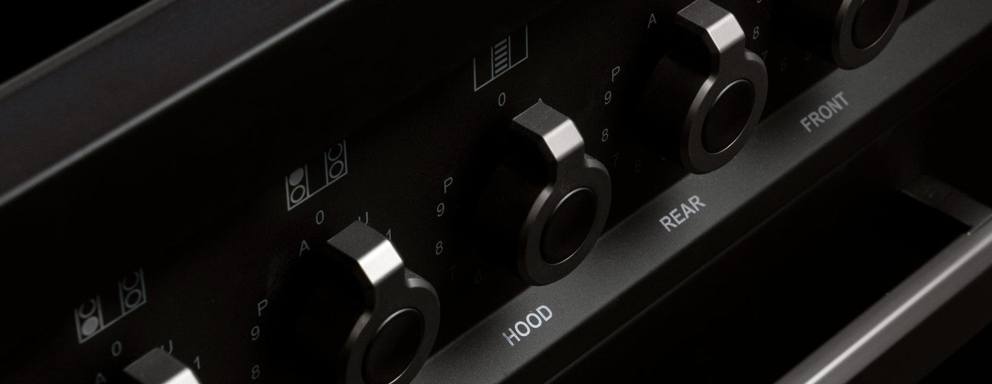 Close-up of black metal control knobs on Air-Tec 90 cm fornuis stove for managing hood, rear, and front zones.