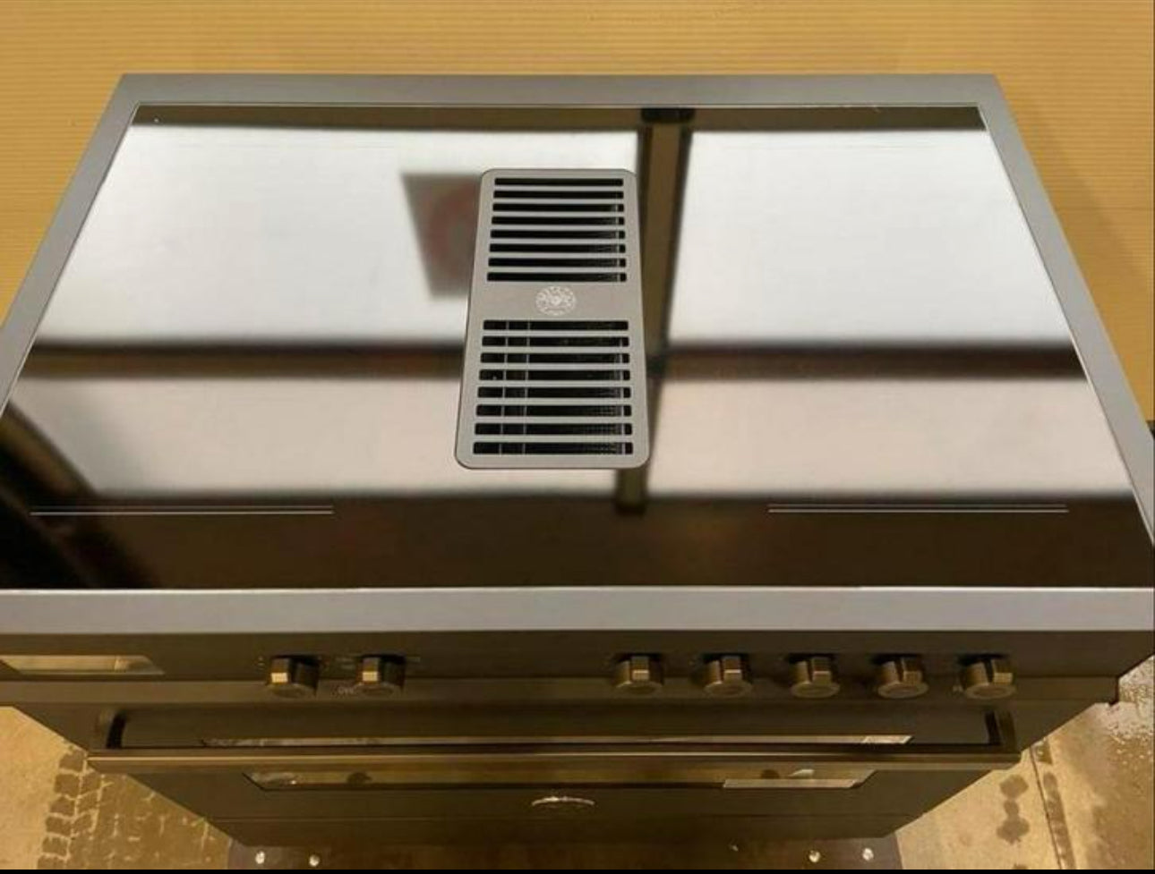 Air-Tec 90 cm fornuis met geïntegreerd afzuigsysteem en inductiekookplaat met metalen knoppen.
